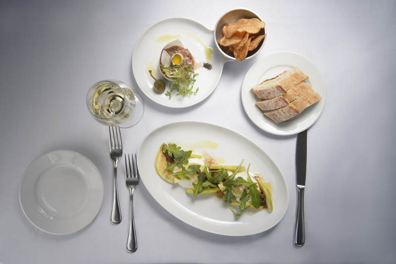 This is a photo of a table set with dinner, a side of bread and a side of chips.