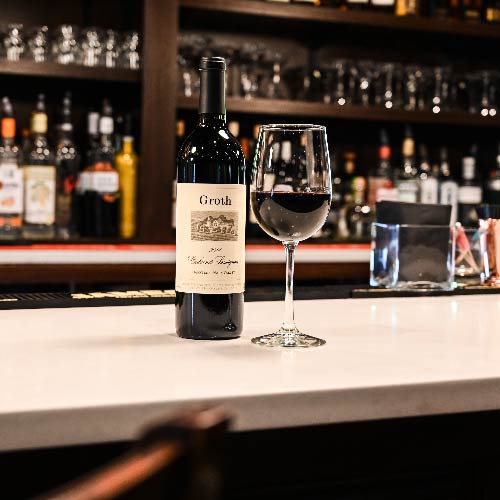 This is a photo of a bottle of red wine and a glass of red wine on top of the Federal's new bar in their bar area.